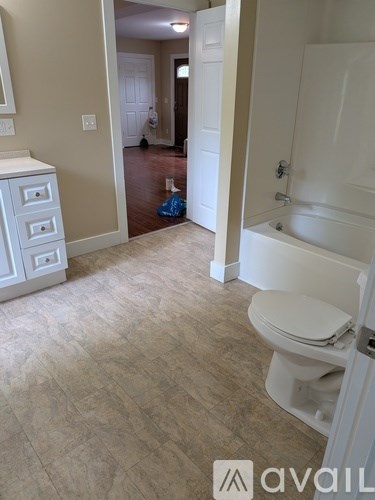 A bathroom with a toilet and a tub in it.