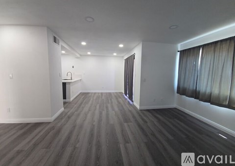 A spacious room with wooden flooring and white walls.