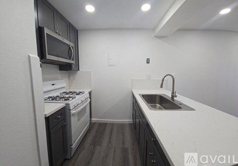 A kitchen with a stove top oven, microwave, and sink.
