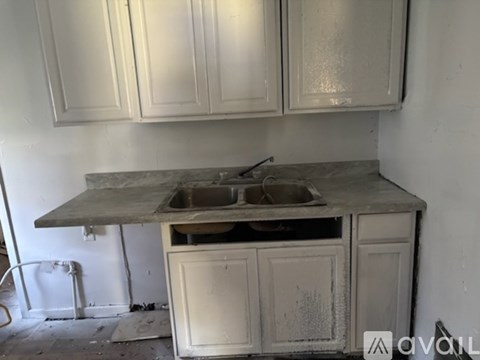 A dirty kitchen with a sink and cabinets.