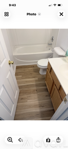 A white toilet is in a bathroom with wooden floors.