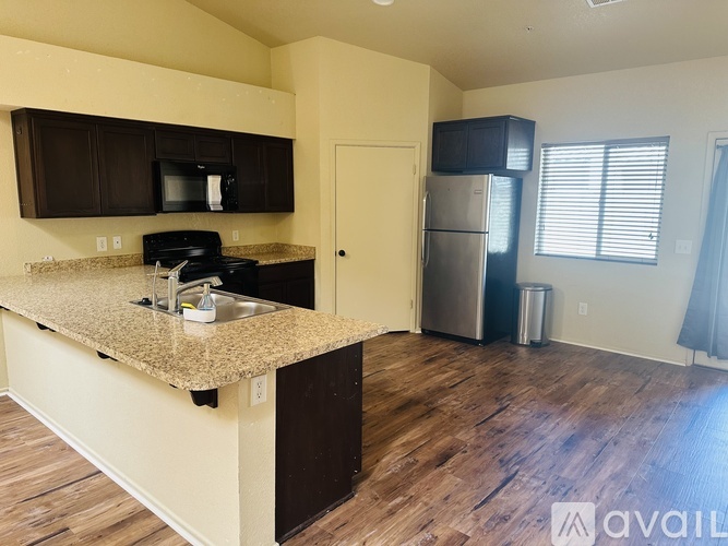 A large, empty room with a kitchenette and a carpeted floor.