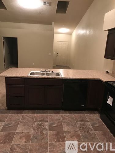 A kitchen with a marble countertop and dark brown cabinets.