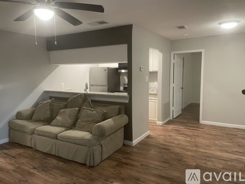 A living room with a couch and a ceiling fan.