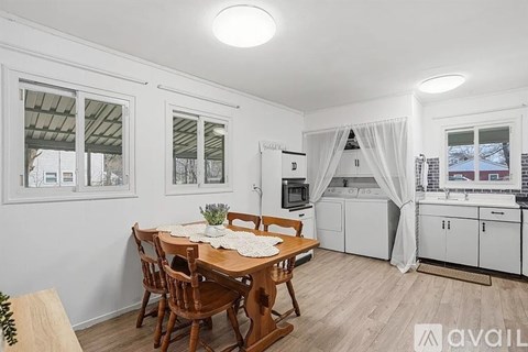 A kitchen with a table and chairs in the foreground and a window with a view of a building in the background.