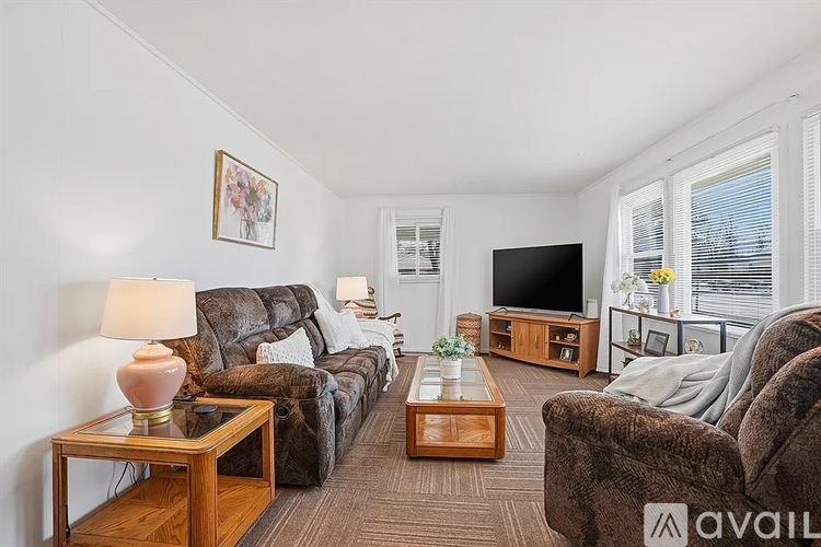 A living room with a brown couch, a wooden coffee table, and a flat screen TV.