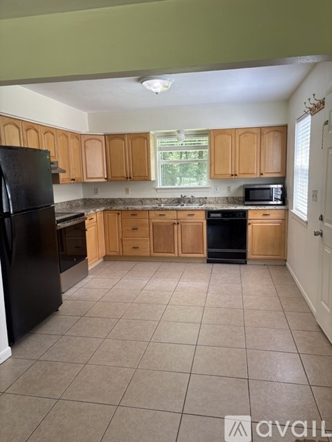 A kitchen with black appliances and wooden cabinets.