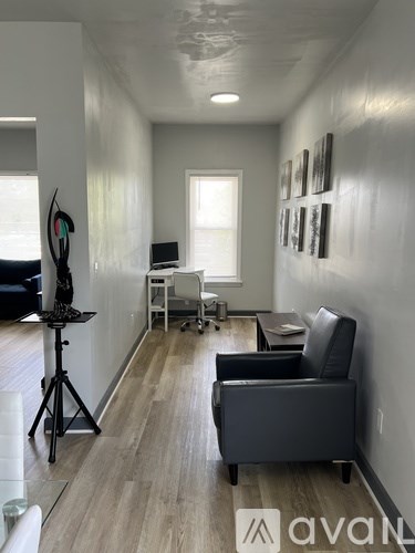 A living room with a black leather chair and a wooden floor.