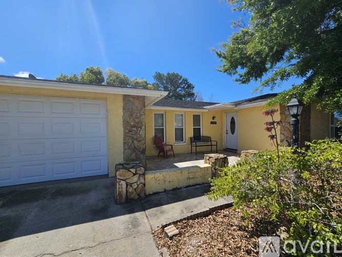 A yellow house with a white garage door and a small porch.