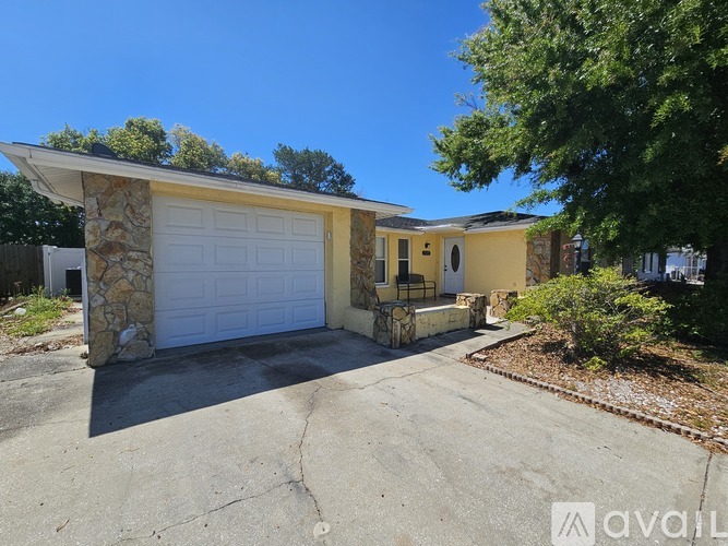 A house with a stone wall and a white garage door is for sale.