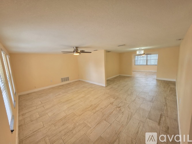 A spacious room with wooden flooring and a ceiling fan.