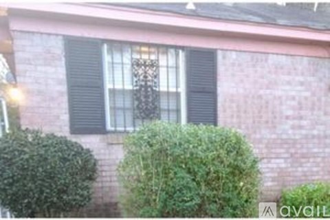 A house with a window and a bush in front.