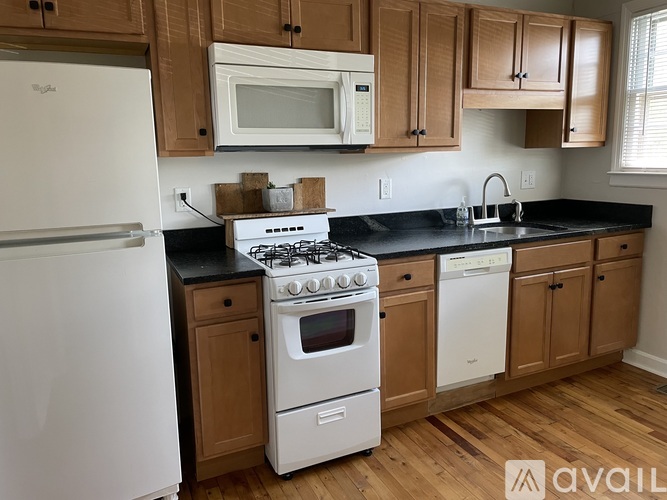 A kitchen with white appliances and wooden cabinets.