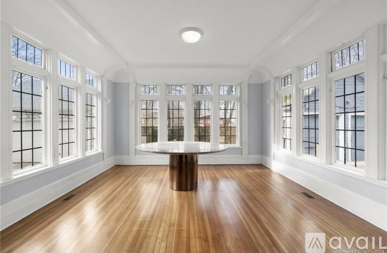 A spacious room with wooden floors and large windows.