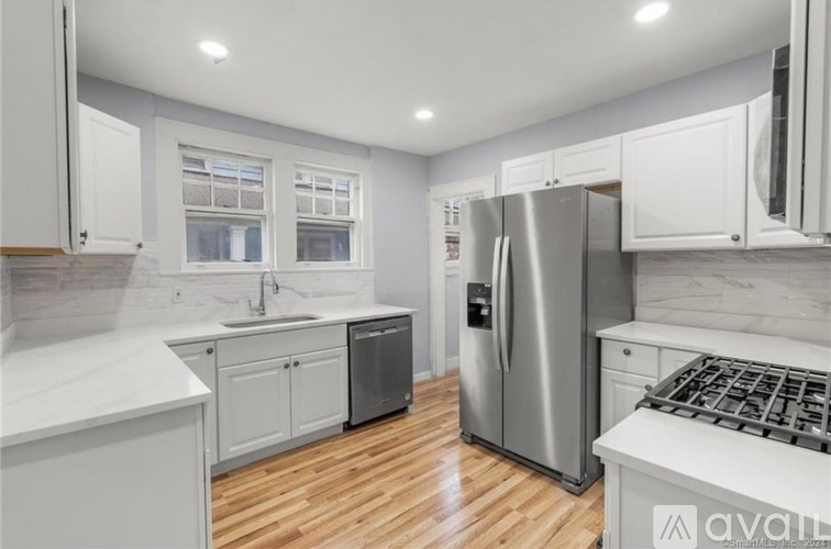 A kitchen with white cabinets and a stainless steel refrigerator.