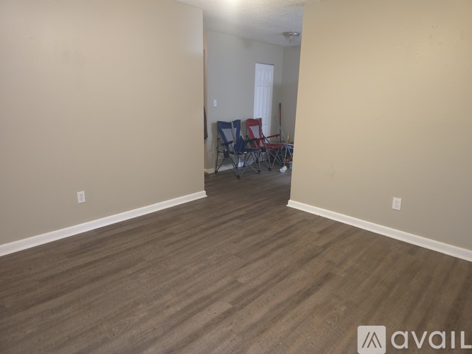 A room with wooden flooring and a wall with a window.