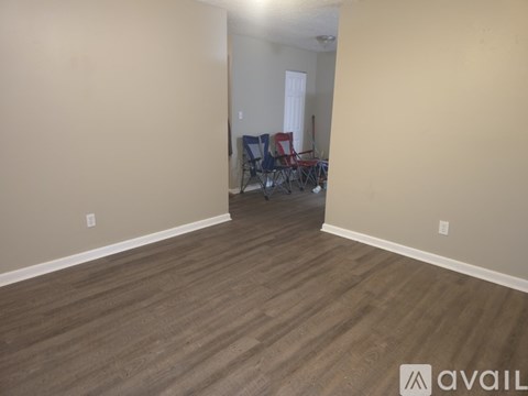 A room with wooden flooring and a wall with a window.