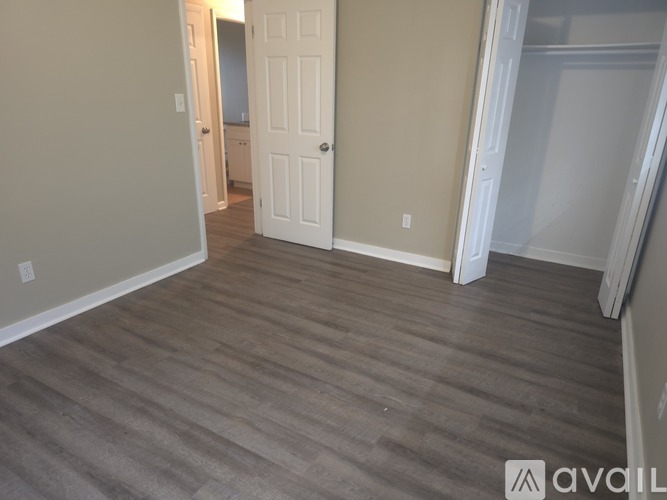 A room with a white door and wooden flooring.