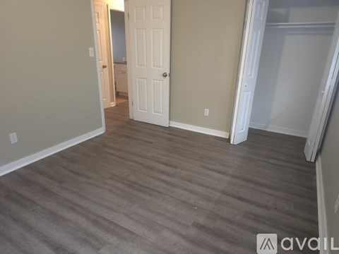 A room with a white door and wooden flooring.