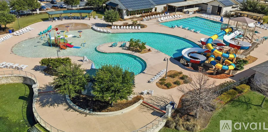 A large outdoor pool with a slide and a water play area.