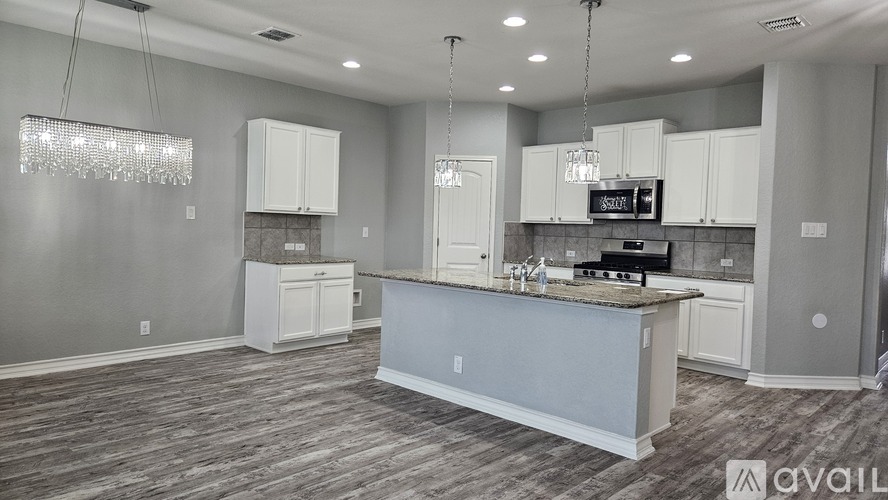 A kitchen with white cabinets and a wooden floor.