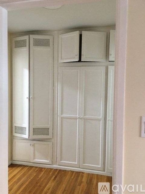 A white kitchen pantry with a wooden floor.