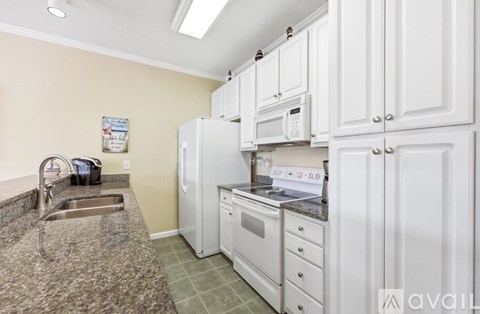 A kitchen with white cabinets and appliances, a sink, and a microwave.