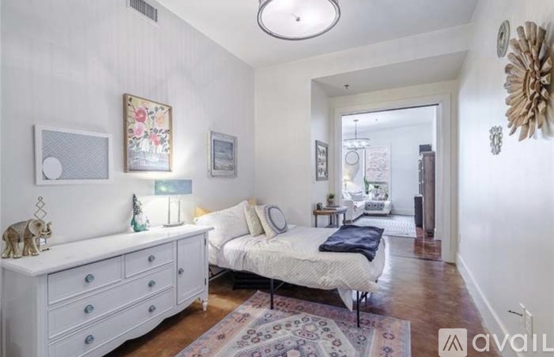 A bedroom with a white bed and a white dresser with a mirror above it.