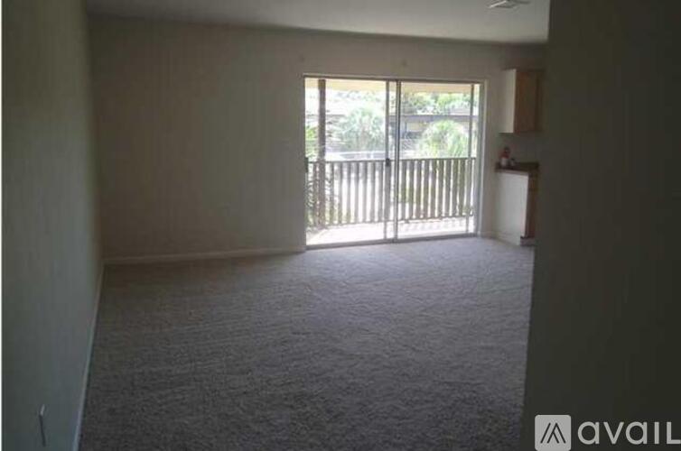 A room with a carpeted floor and a window with blinds.