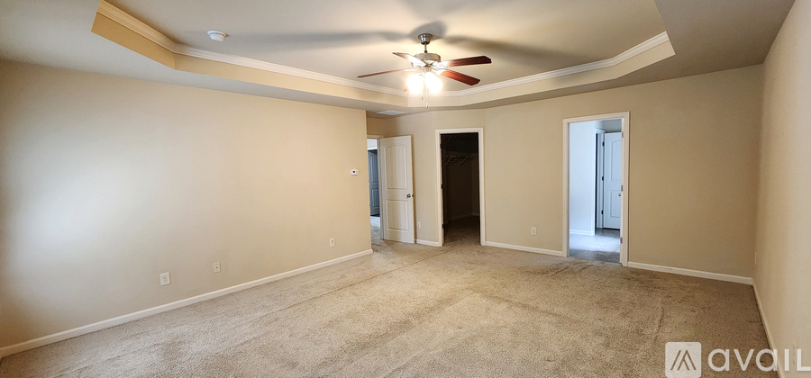 A spacious room with a ceiling fan and carpeted floor.