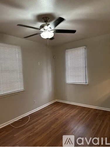 A room with a ceiling fan and wooden flooring.