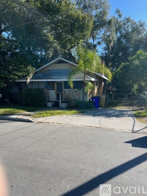 A house with a blue trash can in front of it.