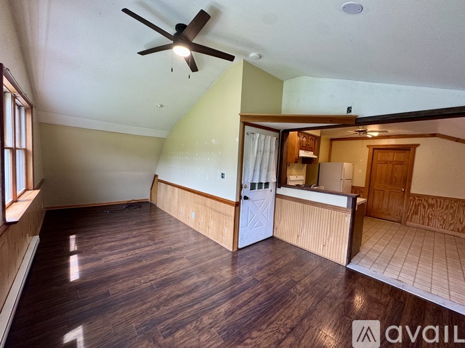 A room with a ceiling fan and wooden flooring.