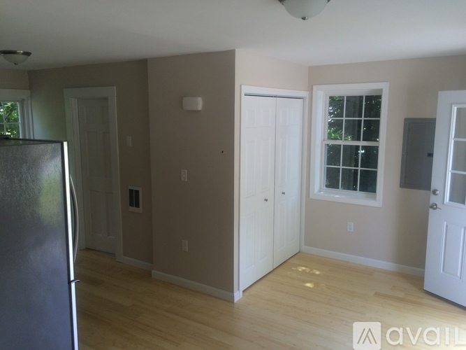 A kitchen with a fridge on the left and a window on the right.