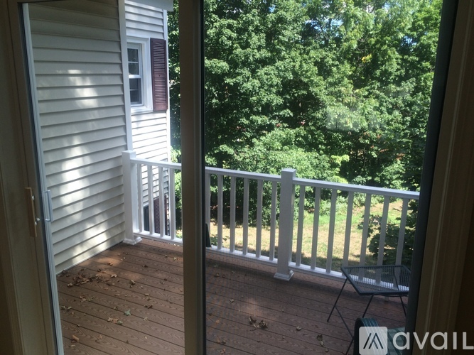 A balcony with a white railing and a view of trees.
