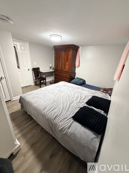 A bedroom with a bed, chair, and cabinet.