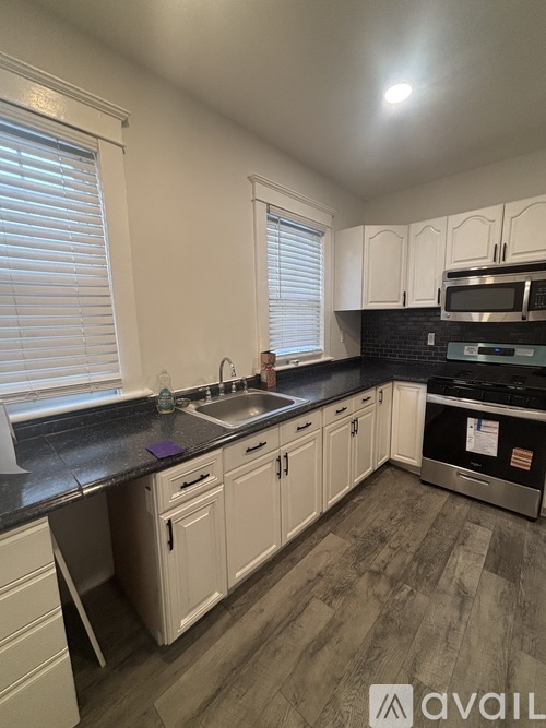 A kitchen with white cabinets and a black countertop.