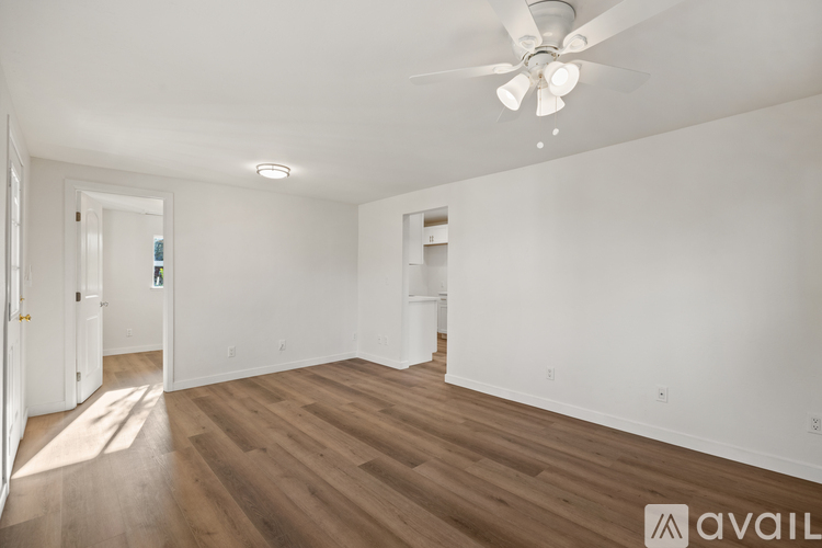 A spacious room with wooden flooring and a ceiling fan.