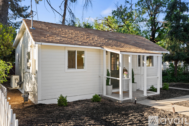 A white house with a brown roof and a white picket fence.