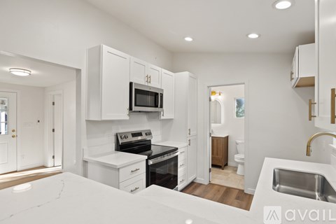 A modern kitchen with white cabinets and appliances.