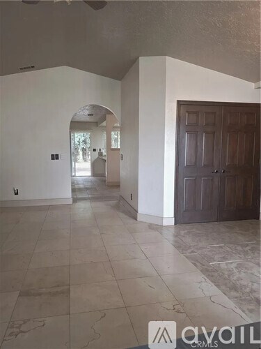 A spacious room with a marble floor and a large archway leading to another room.