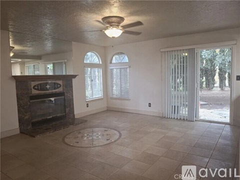 A living room with a fireplace and a ceiling fan.
