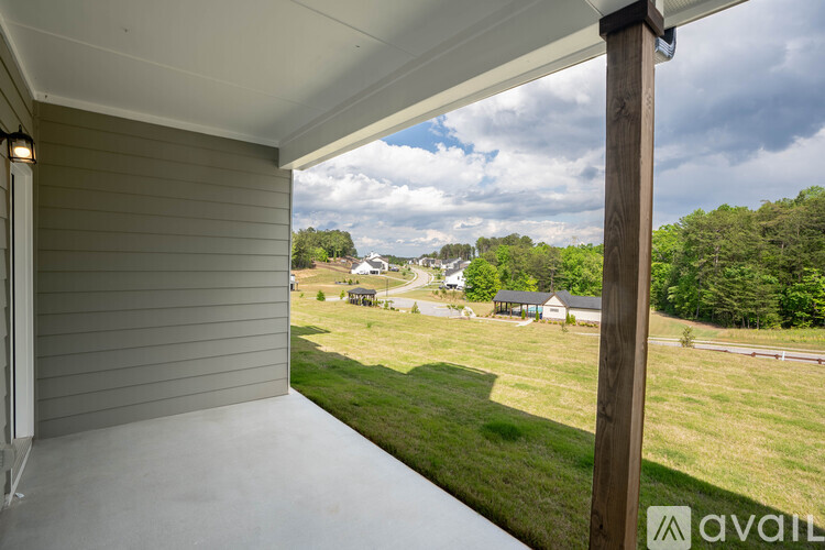 A view from a covered porch looking out to a grassy yard and houses.