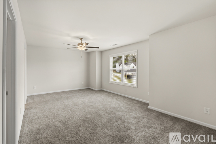 A spacious room with a ceiling fan and a window with blinds.