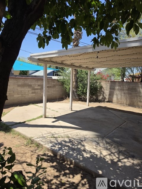 A patio with a white roof and a concrete floor is covered in shadows.