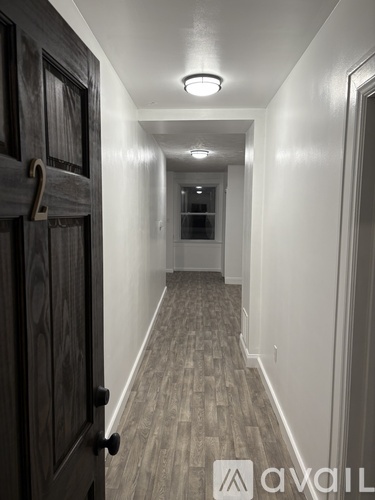 A hallway with a wooden door on the left and a carpeted floor.