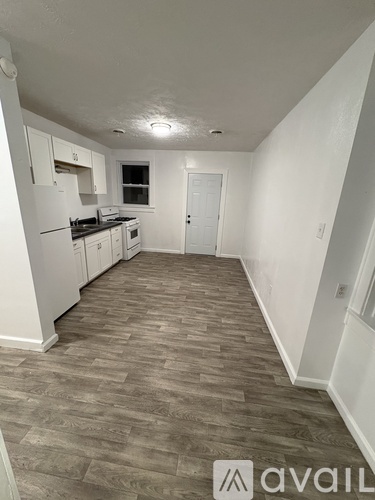 A kitchen with white cabinets and a wooden floor.