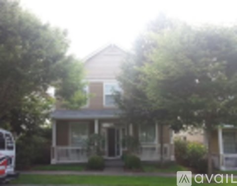 A house with a porch and a tree in front of it.