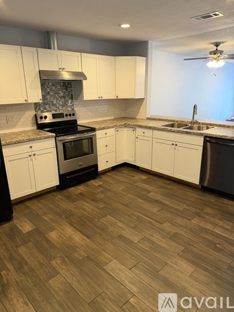A kitchen with white cabinets and a wood floor.