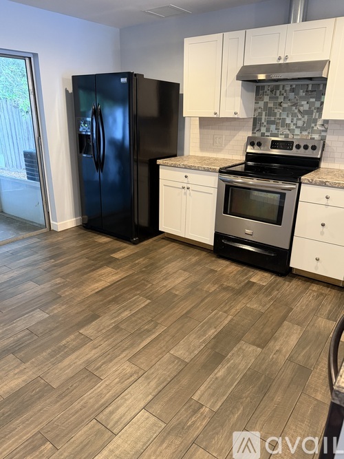 A kitchen with a black fridge and stove top oven.